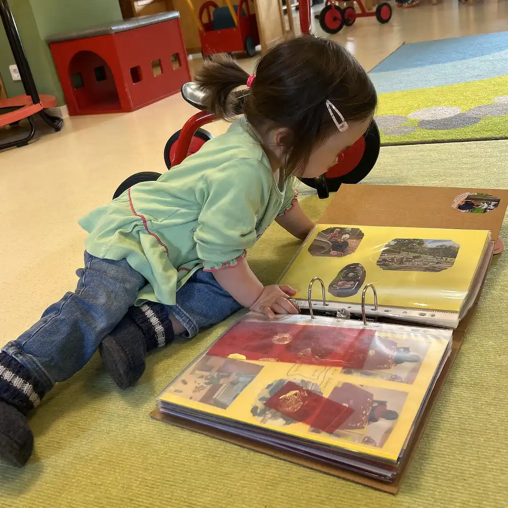 Kind schaut sich sein Portfolio an mit seinen Bildern und Basteleinen der letzten Wochen.