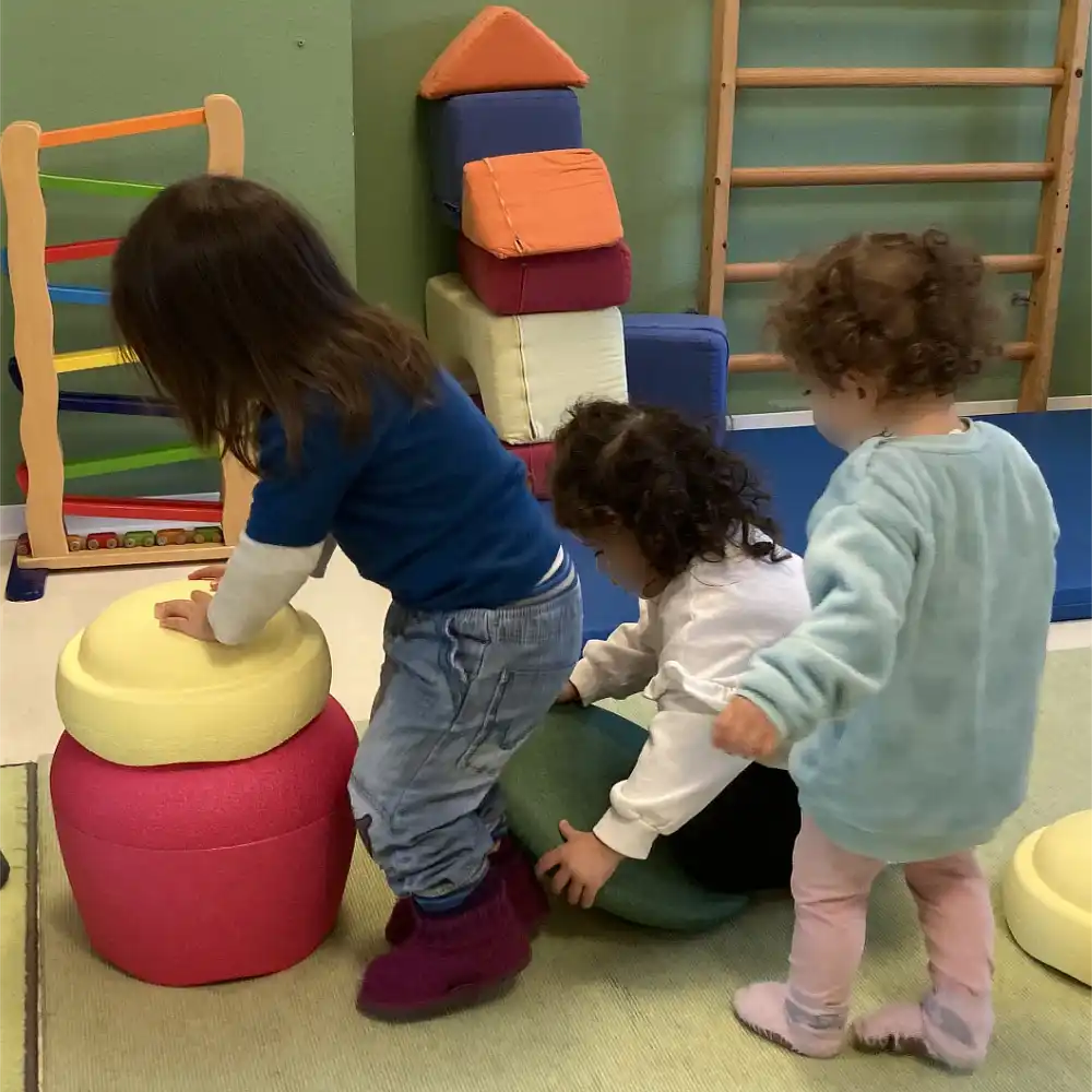 Kinder erkunden Bauklötze und bauen daraus Türme.