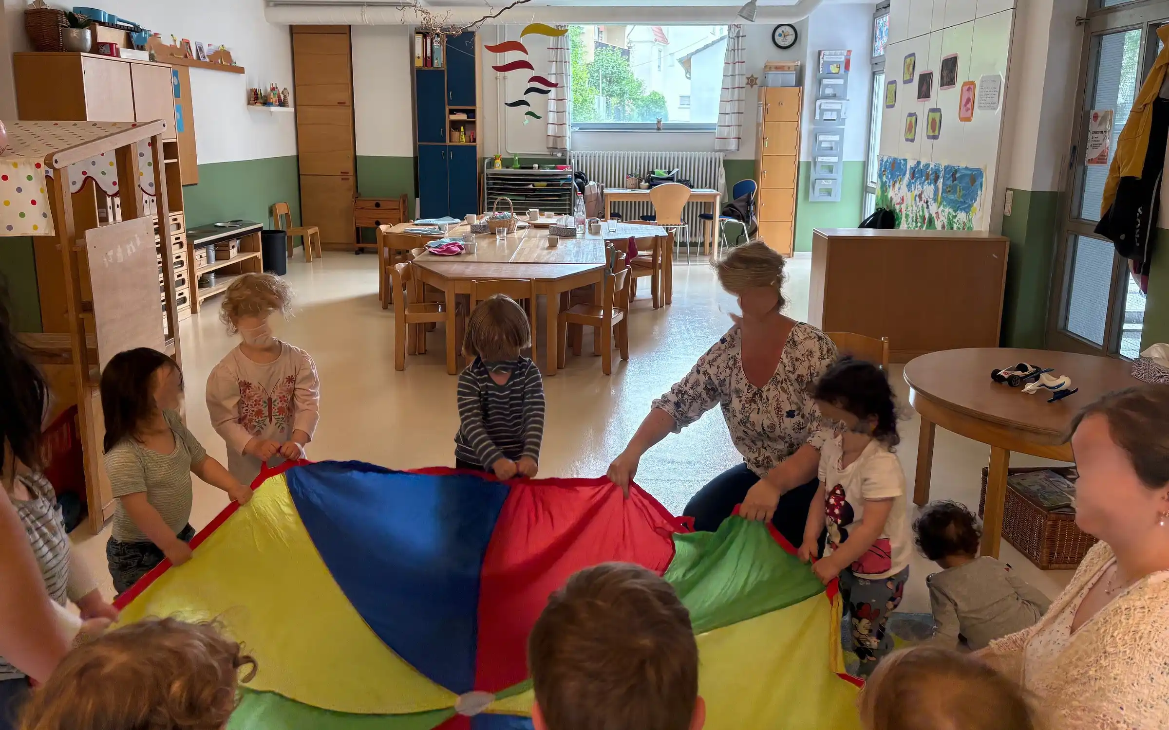 Kinder und Mitarbeitenden nehmen sich ausgiebig Zeit für ein Kinder und Mitarbeitenden nehmen sich ausgiebig Zeit für ein gemeinsames Spiel in der Gruppe.gemeinsames Spiel in der Gruppe.