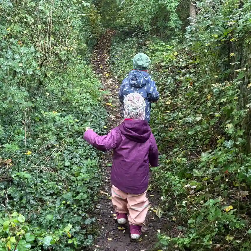 Zwei Kinder mit Matschkleidung wandern auf einem Wanderweg in den Weinbergen von Rohracker